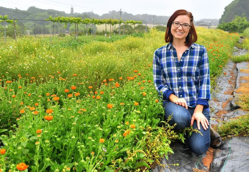 Noelle Joy, herb garden manager at UGArden in Athens, poses beside the calendula at UGArden. CONTRIBUTED BY CHRIS HUNT PHOTOGRAPHY