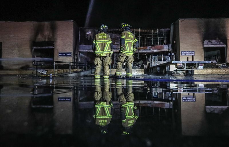 Crews with the South Fulton Fire and Rescue Department work to put out hot spots after a massive fire in the Atlanta Custom Ironworks warehouse early Tuesday morning. 