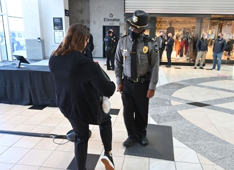 Kenyonn Wallace, security with the mall, inspects a bag after a metal detector alarmed at Lenox Square on December 29, 2020. Lenox Square, in the heart of Buckhead, was the site of numerous shooting incidents that year. The Atlanta Police Department has a mini-precinct inside the mall, which has increased security in recent months.  (Hyosub Shin / Hyosub.Shin@ajc.com)
