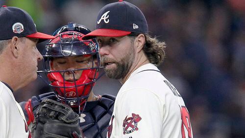 Atlanta Braves starting pitcher R.A. Dickey (right) meets with coach Chuck Hernandez (left) and catcher Kurt Suzuki on the mound during the third inning Saturday, Sept. 16, 2017, against the New York Mets in Atlanta.