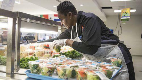 Kitchen food service worker Lola Thomas sets out salads for students in the cafeteria at Heards Ferry Elementary School in Sandy Springs. Local nonprofit All for Lunch paid off student lunch debt at hundreds of schools across metro Atlanta. (Alyssa Pointer / AJC file photo)