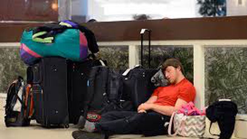 Matt Bell, of Flowery Branch, Ga., rests next to his luggage as he sits out a six-hour delay trying to get to Salt Lake City for a ski trip during an FAA-ordered ground stop at Hartsfield-Jackson International Airport when a winter storm moved into the South bringing a mix of snow, sleet and rain Wednesday, Feb. 25, 2015, in Atlanta. (AP Photo/David Tulis)