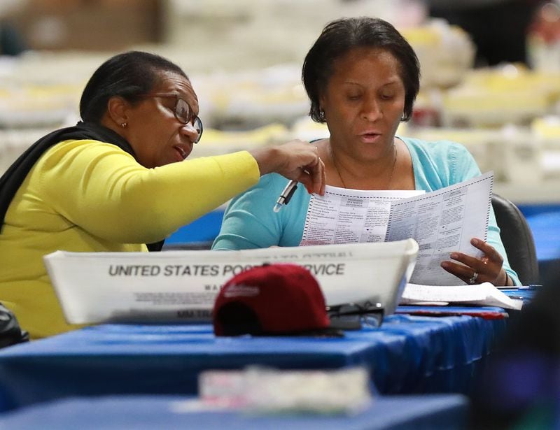Workers examine ballots at the Fulton County Election Preparation Center. CURTIS COMPTON / CCOMPTON@AJC.COM