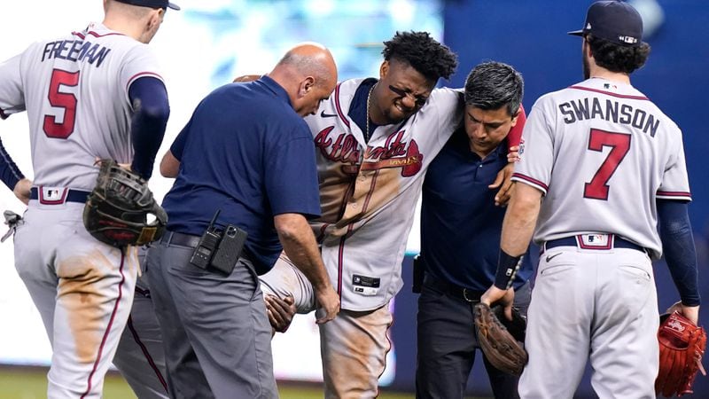 Braves right fielder Ronald Acuna (center) is carried to a medical cart after trying to make a catch on an inside-the-park home run hit by Miami Marlins' Jazz Chisholm Jr. during the fifth inning Saturday, July 10, 2021, in Miami. Acuna injured his right knee on the play.