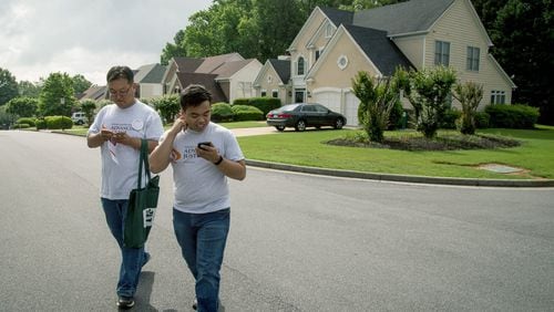 Volunteer Jongwon Lee, left, and Asian Americans Advancing Justice program associate Raymond Partolan walk Saturday through a Johns Creek neighborhood talking with residents about the 6th Congressional District’s new May 21 voter registration deadline. STEVE SCHAEFER / SPECIAL TO THE AJC