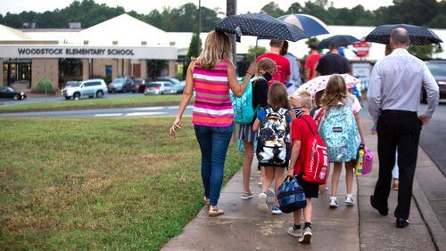 Parents walk their children to the entrance of Woodstock Elementary School in Cherokee County on the first day of school on August 3, 2020.  STEVE SCHAEFER FOR THE ATLANTA JOURNAL-CONSTITUTION