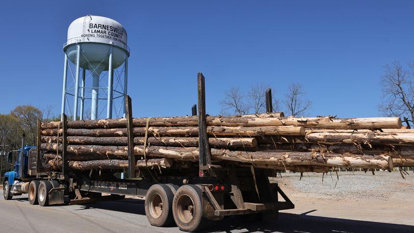 A log truck drives by the Barnesville water tower earlier this month. The state Senate Transportation Committee voted Monday in favor of legislation that would allow trucks hauling forestry and agricultural products to carry heavier loads until July 1, 2024. (Natrice Miller/ Natrice.miller@ajc.com)