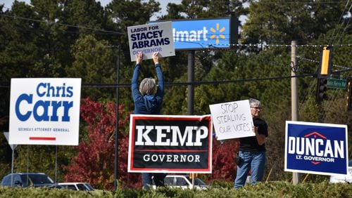 Stacey Abrams fans wave signs at a Towne Lake shopping mall in Cherokee County as GOP gubernatorial candidate Brian Kemp arrives with other statewide Republican candidates on Tuesday. HYOSUB SHIN / HSHIN@AJC.COM