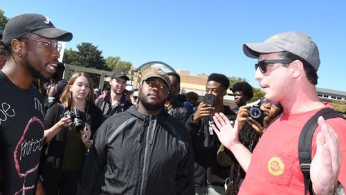 Kyrefe Harper, a senior at KSU (left) majoring in accouting, and Tahir Upshaw, a junior, (center) majoring in mechanical engineering, speak with counter-protester Neil Wolin, a junior (right) majoring in professional sales, at KSU on October 19, 2017. A group of Kennesaw State University students are protesting in support of the KSU cheerleaders who want to take a knee in protest of police brutality during the national anthem. Rebecca Breyer
