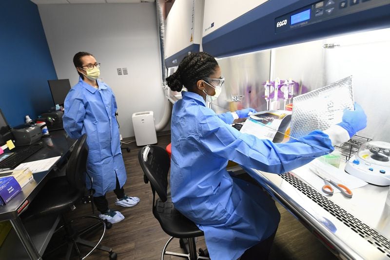 Leah Roberts opens up a delivery of COVID-19 samples for testing from a local practice as fellow Molecular Biologist Aubrey Kellison looks on, at Ipsum Diagnostics labratory on Monday, March 23, 2020. JOHN AMIS /FOR THE AJC
