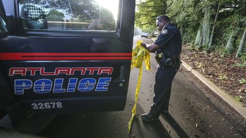 June 23, 2017 Atlanta: Atlanta police officer E. Irby picks up crime tape from Osborne Street where a deadly shooting occurred overnight.  JOHN SPINK/JSPINK@AJC.COM.