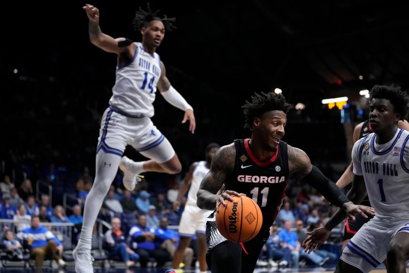 Georgia guard Justin Hill (11) drives between Seton Hall guard Dre Davis (14) and guard Kadary Richmond (1) in the first half of an NCAA college basketball game in the semifinals of the NIT, Tuesday, April 2, 2024, in Indianapolis. (AP Photo/Michael Conroy)