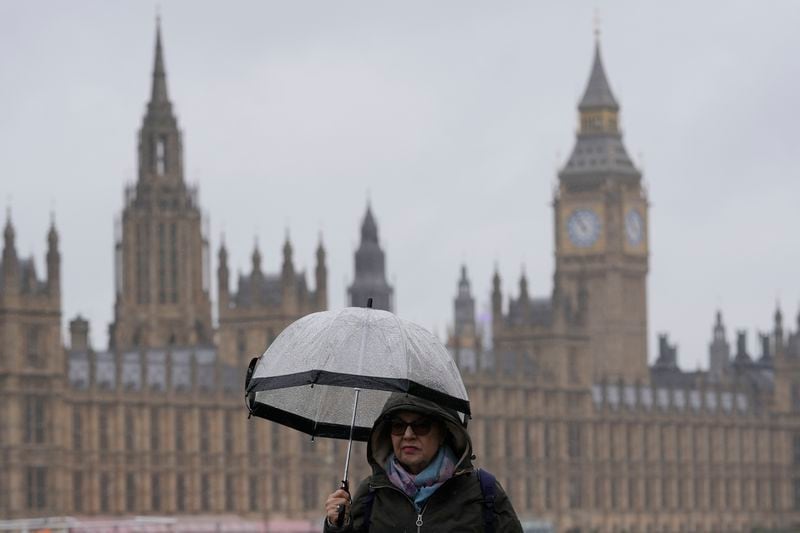 A woman holds an umbrella as she walks along the banks of the River Thames opposite the Houses of Parliament in London, Friday, May 3, 2024. Britain's governing Conservative Party is suffering heavy losses as local election results pour in Friday, piling pressure on Prime Minister Rishi Sunak ahead of a U.K. general election in which the main opposition Labour Party appears increasingly likely to return to power after 14 years. (AP Photo/Kin Cheung)