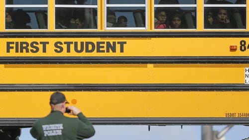 Kids watch a police officer investigate their school bus that collided with another bus on Jan. 26 in Wichita, Kan. According to police, 27 children suffered minor injuries. Legislative momentum in a number of states is building behind seat belt requirements on school buses. (Travis Heying/Wichita Eagle/TNS)