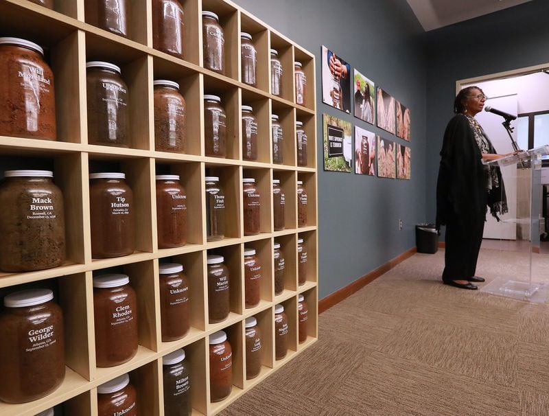 Jars of soil from lynching sites line the wall in the exhibit “Stories From the Soil” while Sheila Joyner-Pritchard, speaking May 5 at the Auburn Avenue Research Library in Atlanta, tells the story of her great-grandfather’s lynching. The Fulton County Remembrance Coalition has collected soil from 35 documented incidents of racial lynchings and murders. CURTIS COMPTON / CCOMPTON@AJC.COM