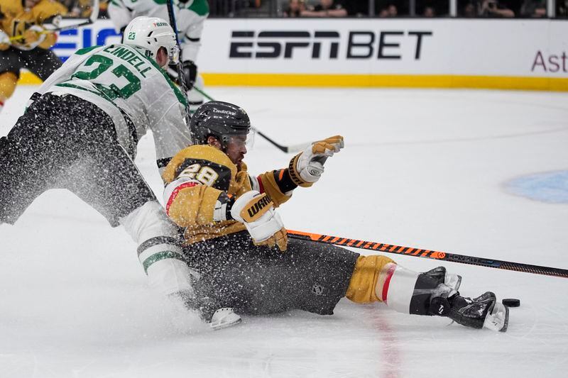 Dallas Stars defenseman Esa Lindell (23) knocks down Vegas Golden Knights left wing William Carrier (28) during the second period in Game 6 of an NHL hockey Stanley Cup first-round playoff series Friday, May 3, 2024, in Las Vegas. (AP Photo/John Locher)