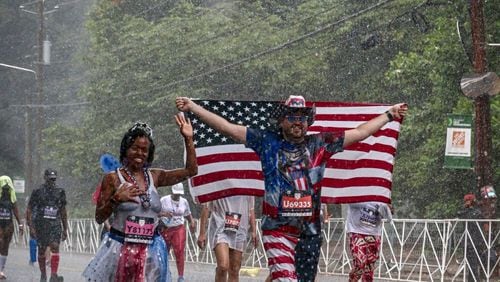 Mark Gorman continued walking in the rain during the Peachtree Road Race Tuesday.