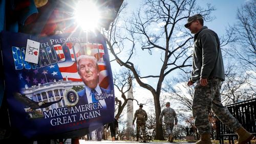 Military personnel walk alongside vendors selling President-elect Donald Trump merchandise on the National Mall in Washington ahead of Friday’s presidential inauguration. (AP Photo/John Minchillo)