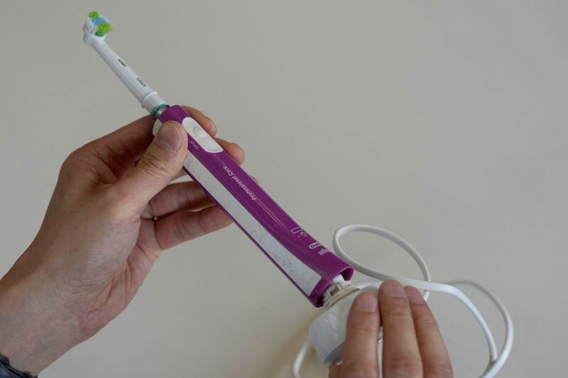 Dismantling an electric toothbrush by twisting the docking station in its port in London, Tuesday, April 30, 2024. Toothbrushes used to be simple, powered only by your hand. Rechargeable electric toothbrushes are increasingly popular because they make brushing more effective but they can be a headache when they stop working properly. Just ask the many people seeking help in online forums when the battery starts giving out.(AP Photo/Frank Augstein)