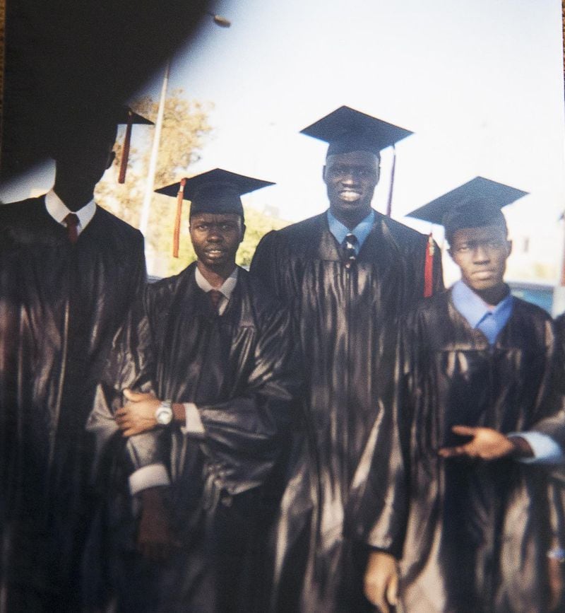 Abraham Deng Ater’s education included degrees from the University of Arizona. A photo of Ater (second from right) and his peers during his undergrad graduation ceremony is displayed at his residence in Snellville. Ater, who works for the Centers for Disease Control and Prevention, also received a master of public health degree from Arizona. ALYSSA POINTER / ALYSSA.POINTER@AJC.COM