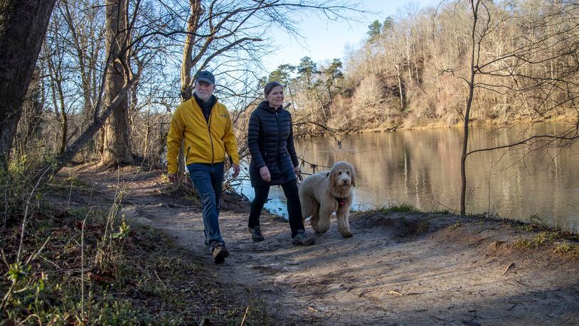 Mary Anne Walser (right) and Jimmy Smith hike with their Golden Doodle Zaha at the East Palisades Trail near the Chattahoochee River in Sandy Springs. The couple began exploring the trails of the Chattahoochee River National Recreation Area after the coronavirus pandemic hit and have logged many miles walking. (Alyssa Pointer / Alyssa.Pointer@ajc.com)