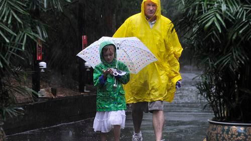 Emma Ferber , 6, and David Ferber, Cumming, walk through the rain at Zoo Atlanta .