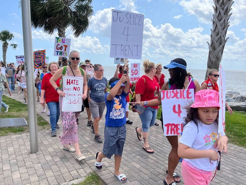 People of all ages march near the water on St. Simons Island Saturday afternoon while holding signs.