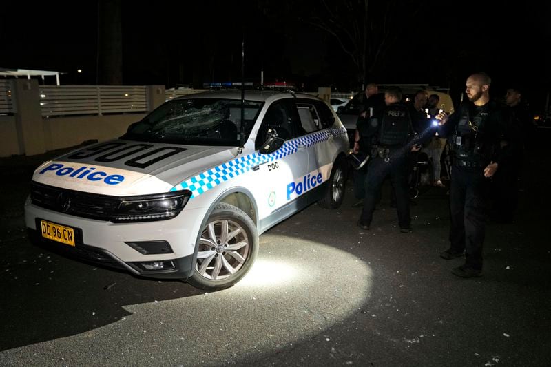 Police officers check vandalized vehicles, including theirs, outside a church where a bishop and churchgoers were reportedly stabbed in Sydney Australia, Monday, April 15, 2024. Police in Australia say a man has been arrested after a bishop and churchgoers were stabbed in the church. There are no life-threatening injuries. (AP Photo/Mark Baker)
