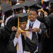 Graduates help each other don hoods at the commencement ceremony at Morehouse College in Atlanta on Sunday, May 19, 2024. (Arvin Temkar / AJC)