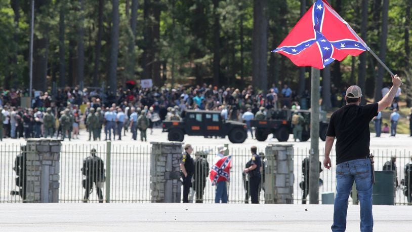 Joseph Andrews, one of a small group with the Rock Stone Mountain rally, waves a Confederate battle flag towards a mass of counter-protesters more than 100 yards away at Stone Mountain Park on Saturday afternoon April 23, 2016. A trove of leaked documents suggests a Russian ‘troll farm’ amplified the conflict prior to the rally. BEN GRAY / AJC