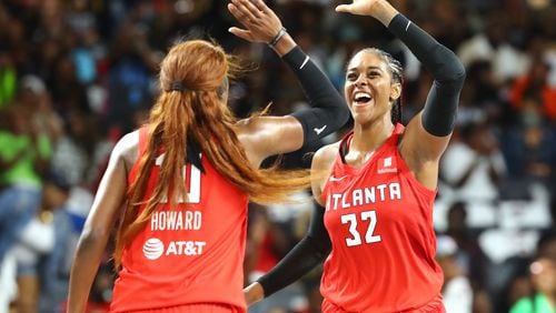 Dream guard Rhyne Howard (left) gets five from forward Cheyenne Parker after making a 3-pointer during a 77-75 victory over the Los Angeles Sparks during their home opener in a WNBA basketball game on Wednesday, May 11, 2022, in College Park.  “Curtis Compton / AJC file”