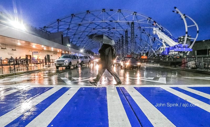 Joe Gronemeyer walks in the rain at the North terminal  at Hartsfield-Jackson International  Airport early Wednesday. JOHN SPINK / JSPINK@AJC.COM