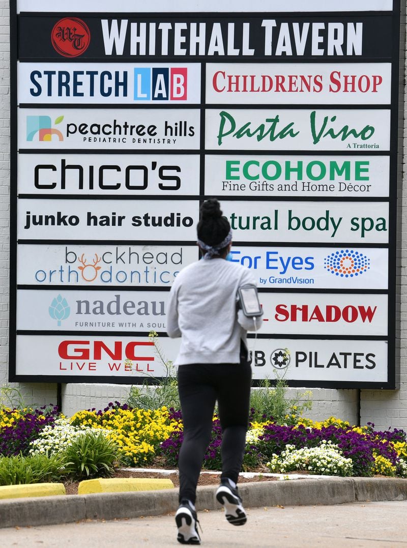 A jogger runs past a big shopping center sign outside Talbots Peachtree Battle Promenade in Atlanta on Tuesday, April 21, 2020. Gov. Brian Kemp will allow gyms, bowling alleys, salons and some other indoor facilities closed under his pandemic shelter-in-place order to resume operations by Friday if they comply with social-distancing requirements. (Hyosub Shin / Hyosub.Shin@ajc.com)