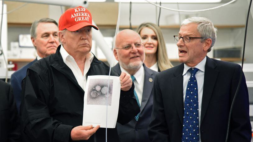 March 6, 2020 Atlanta - President Donald Trump holds a photograph of coronavirus as Dr. Steve Monroe (right) with CDC speaks to members of the press at the headquarters of the Centers for Disease Control and Prevention in Atlanta on Friday, March 6, 2020. President Donald Trump visited the headquarters of the Centers for Disease Control and Prevention in Atlanta on Friday after all, after initially scrapping the trip over concerns that a staffer at the agency had contracted the coronavirus. (Hyosub Shin / Hyosub.Shin@ajc.com)