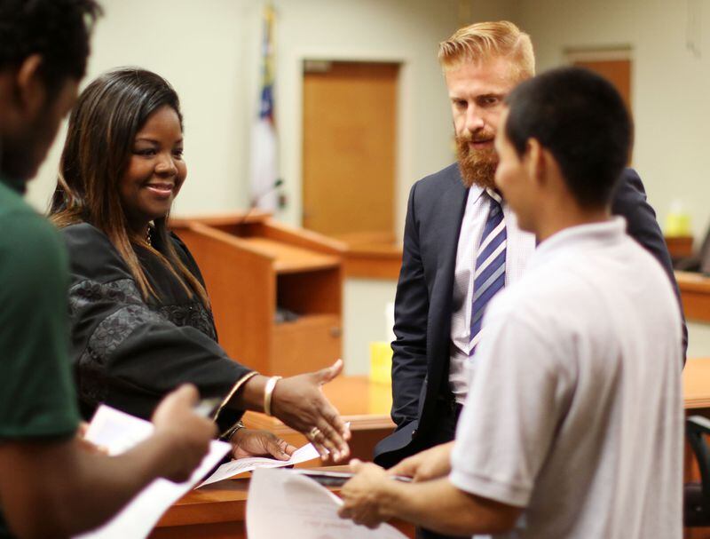 Sep. 18, 2015 - Decatur - Lawyer David Lee Windecher watches two young offenders, Luis Rangel (left) and Donsheldon Lowe,  receive congratulations in Judge Asha Jackson's courtroom as part of  a program in her court for non-violent, first time offenders under the age of 25 called "Project Pinnacle."   Windecher, the son of Argentine immigrants, grew up in a tough, poor neighborhood in Miami where he became a gang member and a drug dealer as a young teenager. He was arrested 13 times and jailed for eight months before he turned 19. Around that time, several things happened that changed the trajectory of his life: He found religion, he met a girl from the other side of the tracks who urged him to make something better of himself, he noticed that his younger siblings were starting to follow his bad example, and his best friend and gang running mate got sentenced to hard time in prison. David enrolled in a local college, still selling a little weed to support himself, and began to wean himself from his gang days. He set his sights on becoming a lawyer and moved to Atlanta to attend John Marshall Law School. It was a long, hard struggle, but he finally graduated and passed the bar exams in Georgia and then Florida, despite his lengthy criminal record. Now a criminal defense attorney in Atlanta, he has written book about overcoming his checkered past -- "The American Dream"   BOB ANDRES  / BANDRES@AJC.COM