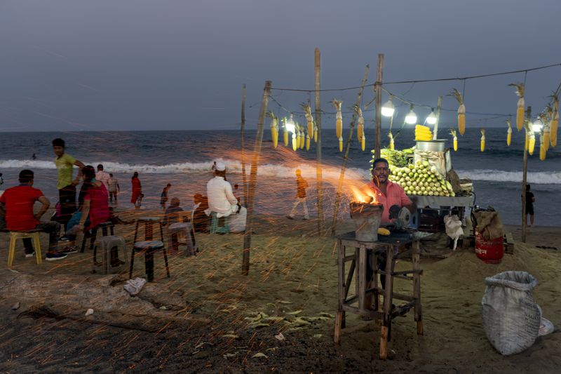 A vendor roasts corn on the cob for people visiting Marina beach in the southern Indian city of Chennai, April 16, 2024. (AP Photo/Altaf Qadri)