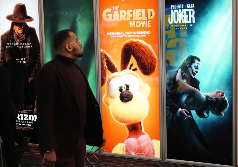 An attendee walks past advertisements for upcoming films including "The Garfield Movie" and "Joker: Folie a Deux" on the opening day of CinemaCon 2024 at Caesars Palace, Monday, April 8, 2024, in Las Vegas. The four-day convention of the National Association of Theatre Owners (NATO) runs through Thursday. (AP Photo/Chris Pizzello)