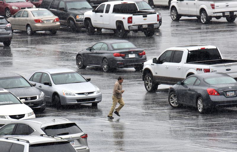 Jan. 6, 2017 Atlanta - A man rushes to avoid the rain in a parking of Lenox Mall in Buckhead on Friday. The winter storm could bring 3 to 4 inches of snow accumulation in the county, officials said. HYOSUB SHIN / HSHIN@AJC.COM