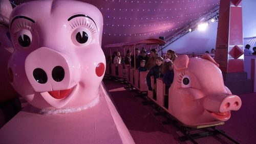 A pink train full of people makes it’s way around the track beneath a 170-foot, 1950s-themed Macy’s Pink Pig tent in this file photo. STEVE SCHAEFER / SPECIAL TO THE AJC