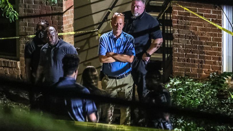 DeKalb County police Sgt. Lynn Shuler (center) looks over the scene of a fatal shooting at the Oak Forest Apartments on Hatton Drive.