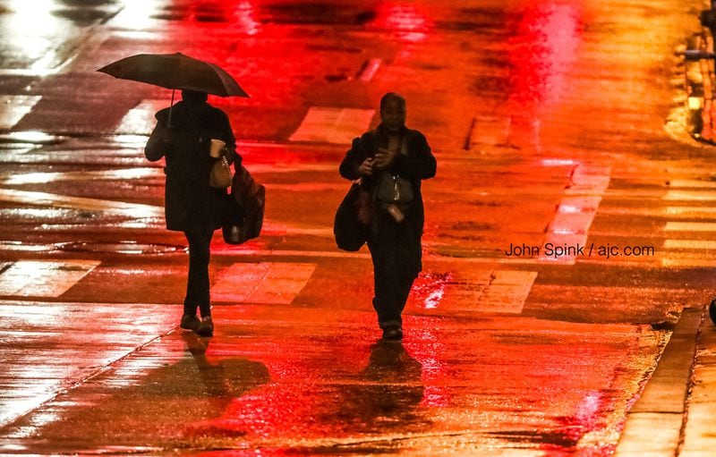Jennifer Mostiller (left) and Brigett Williams walk through the rain Wednesday morning at Peachtree and Decatur streets.