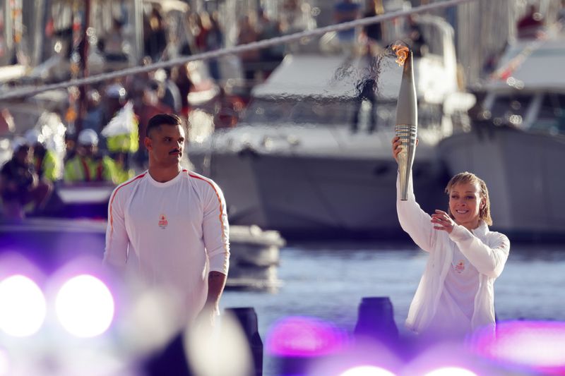 French Paralympic athlete Nantenin Keïta, holds the Olympic torch while French swimmer Florent Manaudou looks on during the torch arrival ceremonyl in Marseille, southern France, Wednesday May 8, 2024. After leaving Marseille, a vast relay route is undertaken before the torch odyssey ends on July 27 in Paris. The Paris 2024 Olympic Games will run from July 26 to Aug.11, 2024. Keita is visually impaired and won a gold medal during the 2016 Olympics in Rio de Janeiro. (Ludovic Marin, Pool via AP)