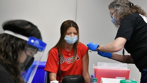 Atlanta Braves fan Emily McCormick of Johns Creek reacts as she receives the Johnson & Johnson COVID-19 vaccine at Truist Park on May 7. (Hyosub Shin / Hyosub.Shin@ajc.com)