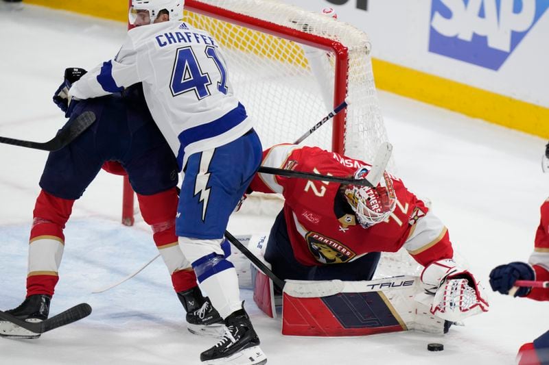 Florida Panthers goaltender Sergei Bobrovsky (72) covers the puck as Tampa Bay Lightning right wing Mitchell Chaffee (41) and center Kevin Stenlund battle for position during the first period of Game 1 of the first-round of an NHL Stanley Cup Playoff series, Sunday, April 21, 2024, in Sunrise, Fla. (AP Photo/Wilfredo Lee)