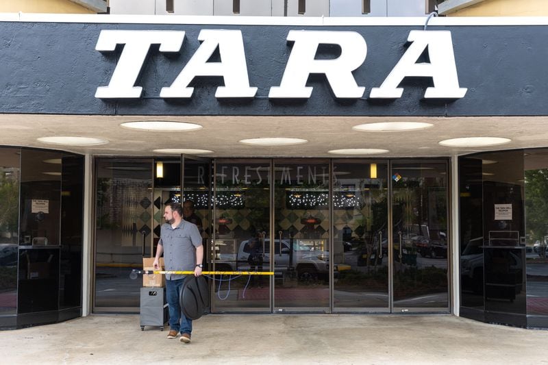 Christopher Escobar, new owner of the Tara Theatre, gets ready to put up the “Grand Reopening” sign outside the Tara in Atlanta on Monday, May 22, 2023. Tara Theatre will reopen on Thursday six months after Regal Cinema abruptly shut it down. (Arvin Temkar / arvin.temkar@ajc.com)