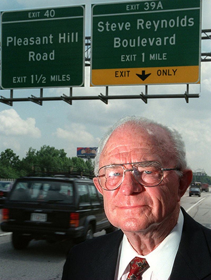 In this 1997 file photo, Former state senator Steve Reynolds stands under his namesake road sign off I-85 in Gwinnett County. AJC