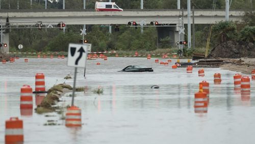 An ambulance responding to a call passes a swamped vehicle on President Street that tried to cross flood waters to Tybee Island during Hurricane Matthew on Saturday, Oct. 8, 2016, in Savannah. Curtis Compton /ccompton@ajc.com