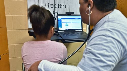 School nurse Satonya Kimbro is measuring 4th grader Sonja Leonard’s pulse rate at Fickett Elementary School via a telehealth device, so pediatric nurse practitioner Martha Cargill can monitor remotely from her clinic on Thursday, December 13, 2018. A new “telehealth” program allows Fickett Elementary School to provide health care services to students, bringing a doctor to students virtually. The program is part of an expanded push by Atlanta Public Schools to provide social services, including health care, to students because officials know it’s not just what happens inside a classroom that impacts student learning. HYOSUB SHIN / HSHIN@AJC.COM