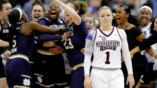 Notre Dame's Arike Ogunbowale is congratulated by teammates as Mississippi State's Blair Schaefer (1) walks away after Ogunbowale made a 3-point basket to defeat Mississippi State 61-58 in the final of the women's NCAA Final Four college basketball tournament, Sunday, April 1, 2018, in Columbus, Ohio. (AP Photo/Tony Dejak)
