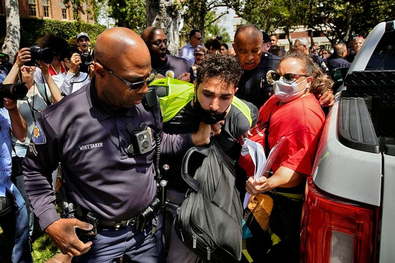 A University of Southern California protester is detained by USC Department of Public Safety officers during a pro-Palestinian occupation at the campus' Alumni Park on Wednesday, April 24, 2024, in Los Angeles. .(AP Photo/Richard Vogel)